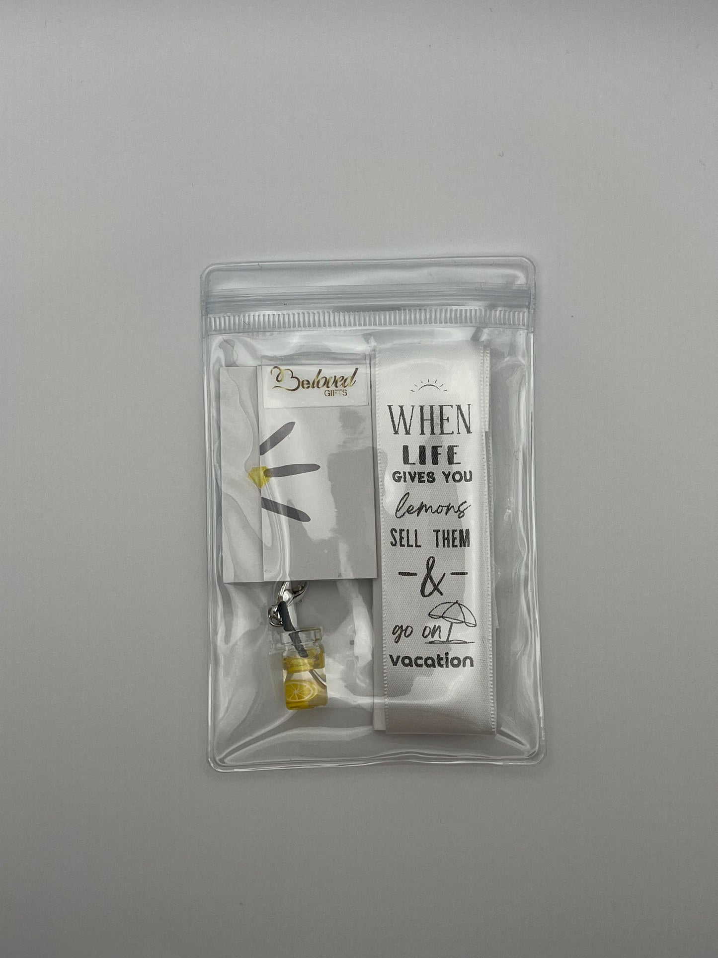 LIFE HUMOUR – “When life gives you lemons, sell them & go on vacation”- White Satin Reusable Adhesive Book-It™ Bookmark with a Charm (Lemonade Cup)